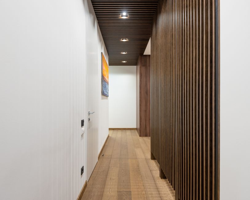 A sleek, contemporary hallway featuring wood paneling and modern lighting fixtures. Best indoor paints for Hallways and High-Traffic areas